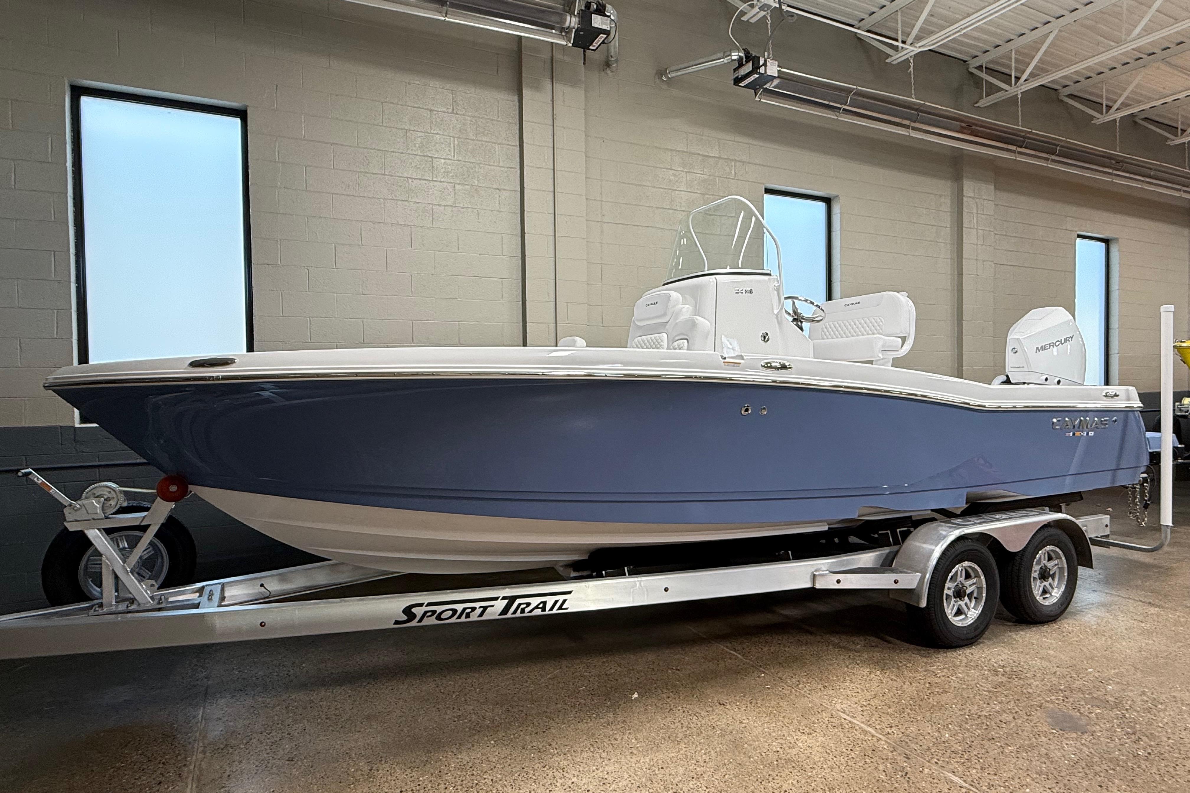 2026 Caymas 24 HB boat on a Sport Trail trailer in a showroom.