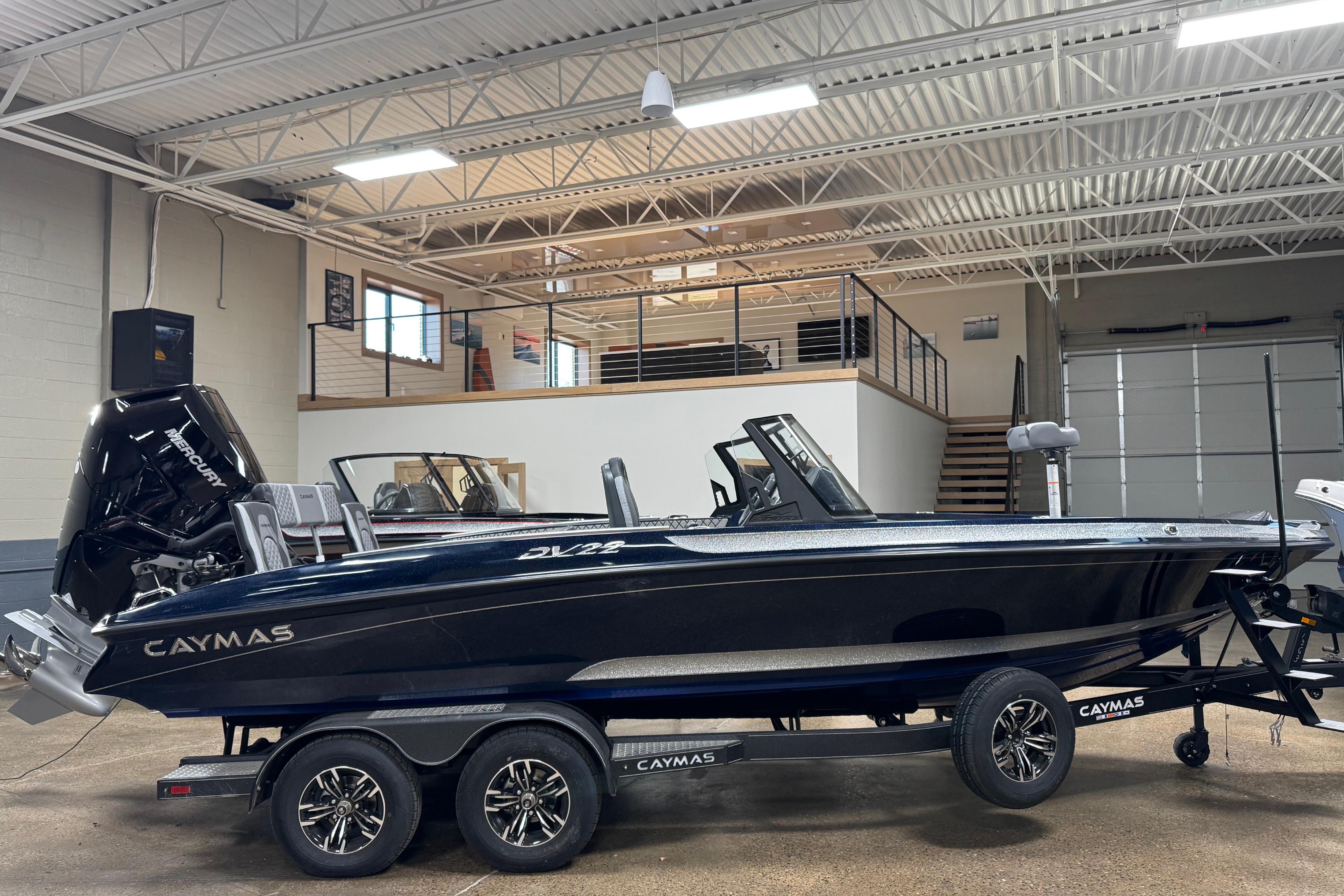2026 Caymas DV 22 boat in showroom, sleek design with dual console and powerful outboard motor.