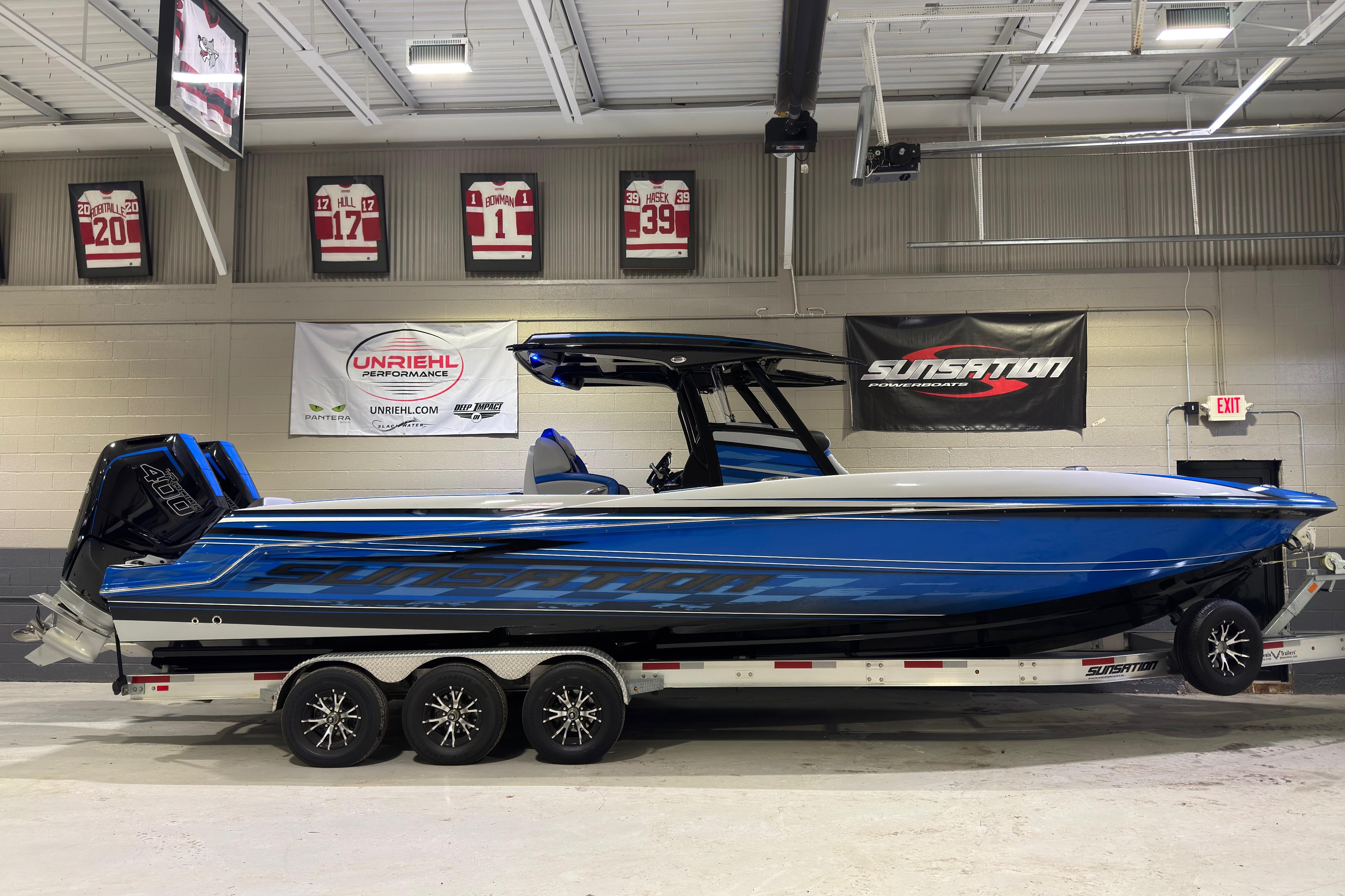 2025 Sunsation 32 CCX powerboat in a showroom, featuring sleek blue and black design.