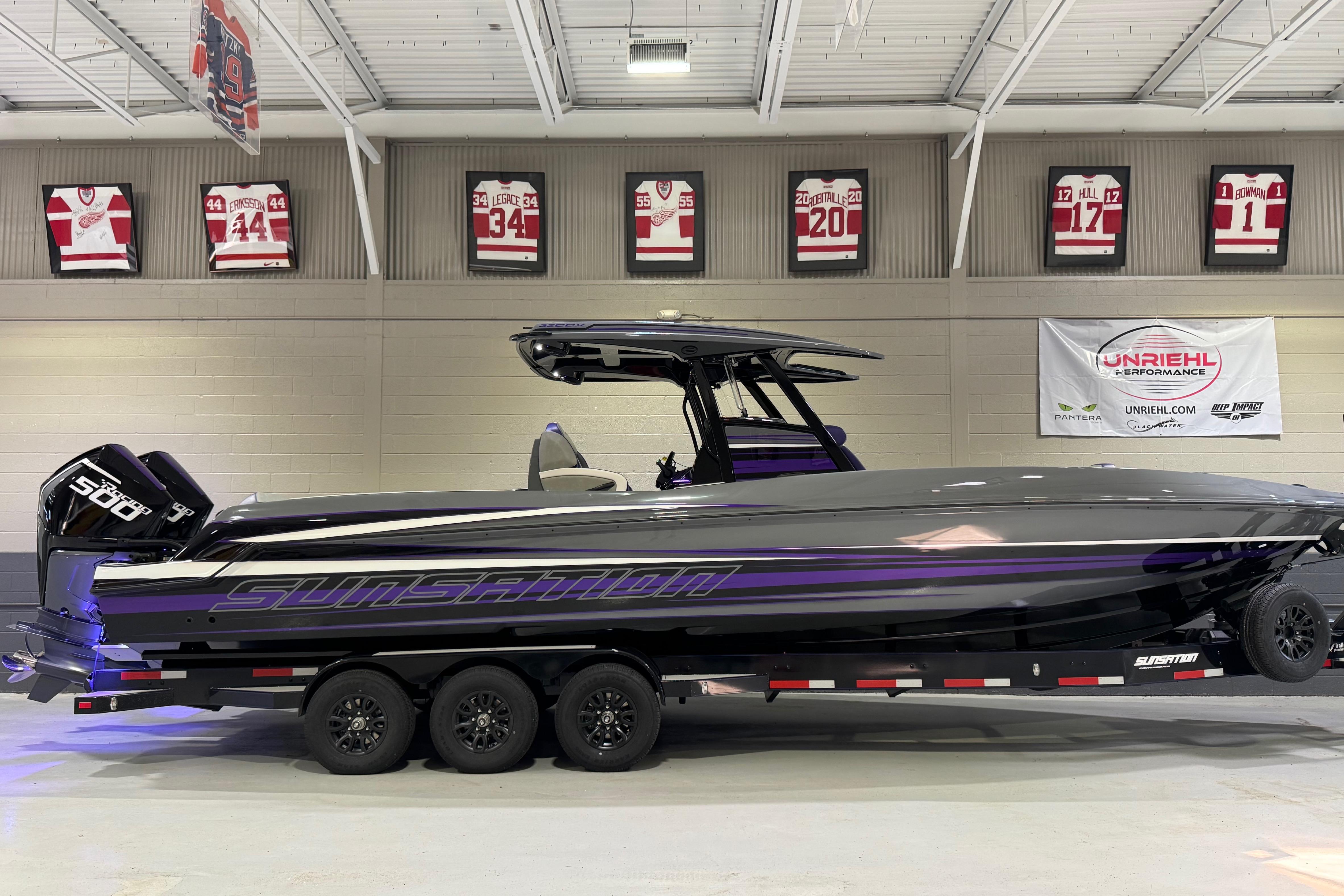 2026 Sunsation 32 CCX boat in showroom, sleek design with purple accents.
